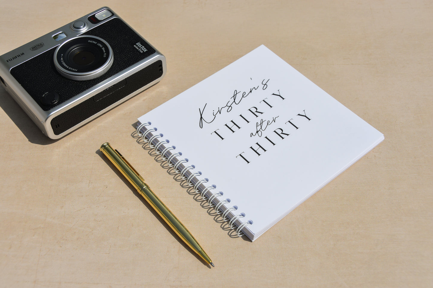 Vintage camera, notebook with text, and pen on a beige surface