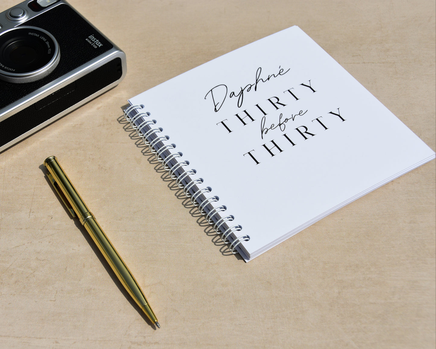 Vintage camera, pen, and notebook on a wooden surface