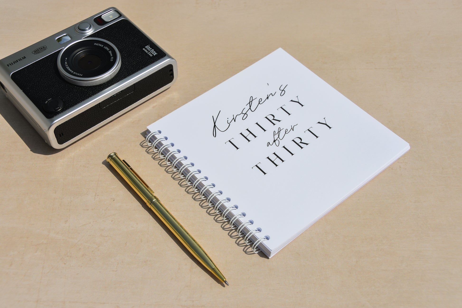 Vintage camera, notebook with text, and pen on a beige surface