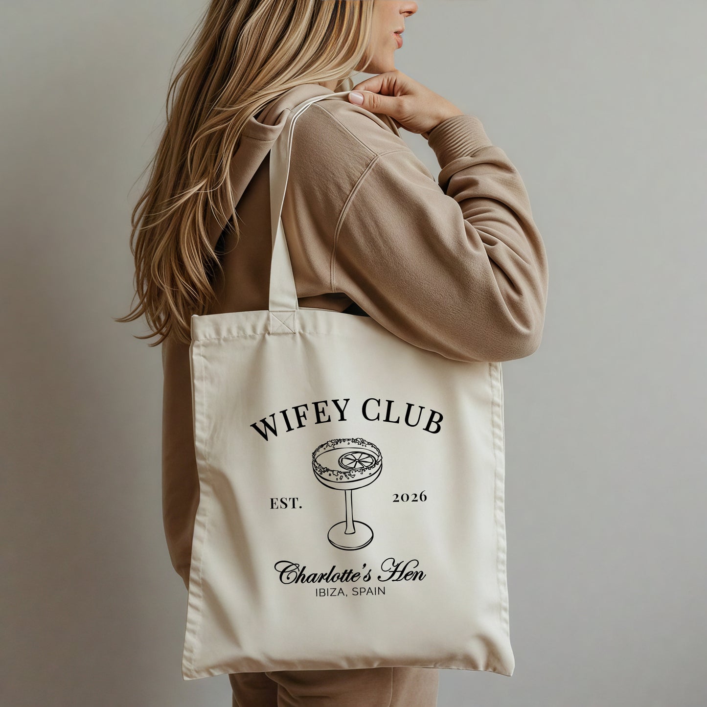 Person holding a tote bag with 'Wifey Club' text and design.