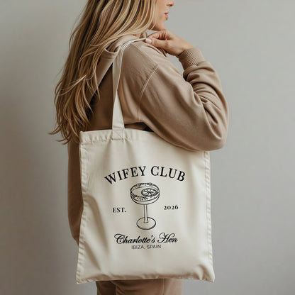 Person holding a tote bag with 'Wifey Club' text and design.