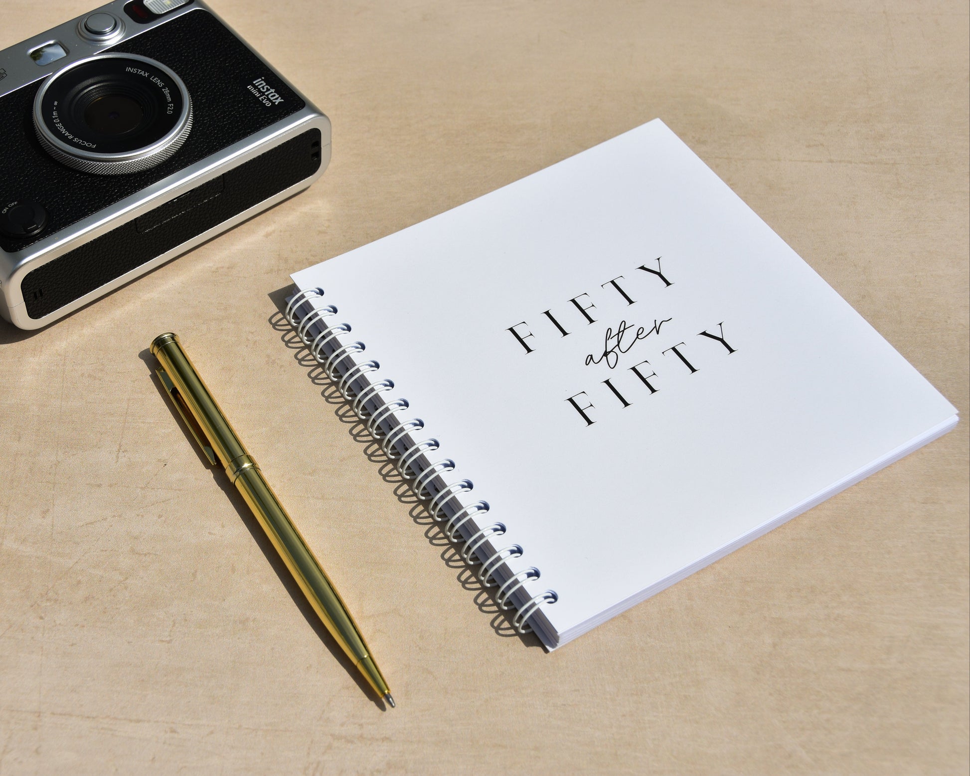 Camera, pen, and notebook on a wooden surface