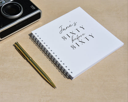 Camera, pen, and notebook on a wooden surface with 'Jane's Sixty Before Sixty' text.